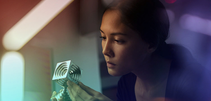 Lady holding and staring at a silver cube